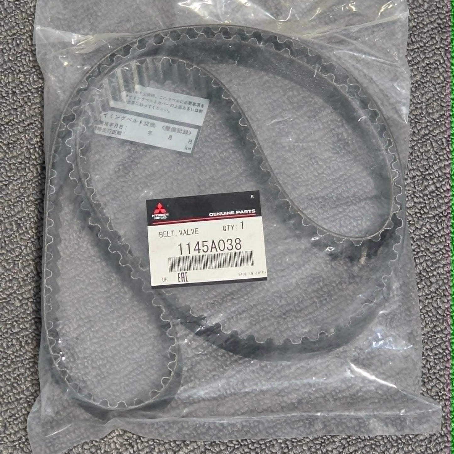 Packaged belt with a label on a textured gray surface