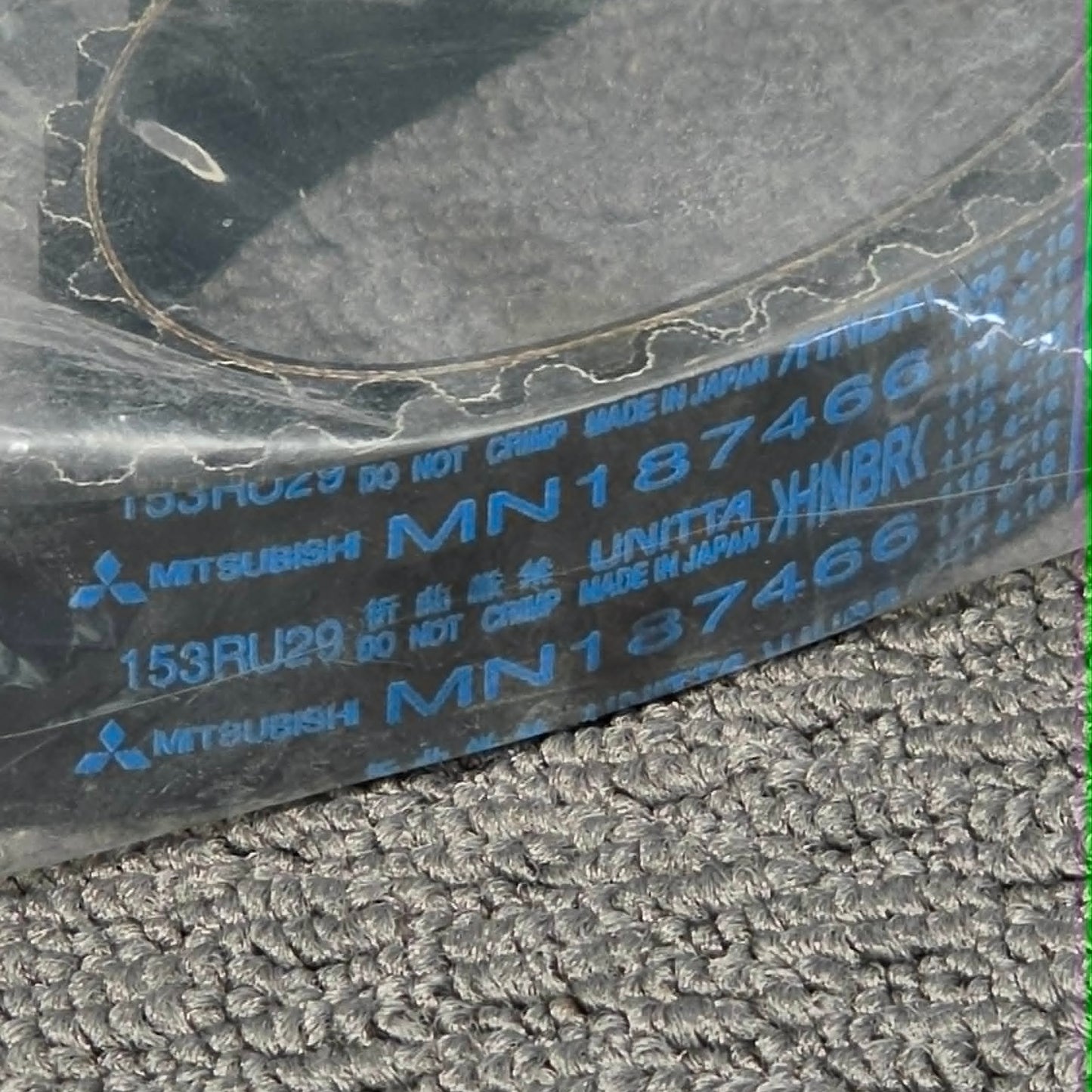 Close-up of a Mitsubishi belt with visible branding on a textured surface